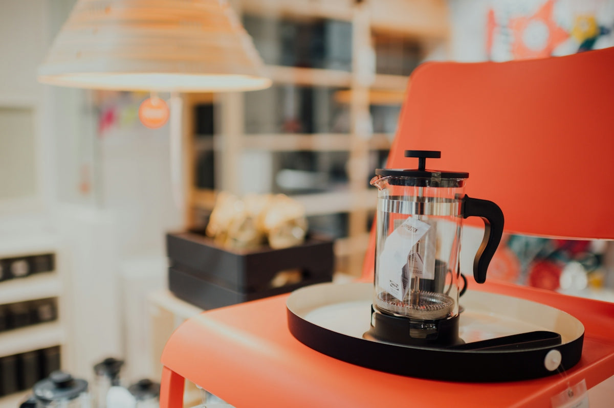 black and clear glass coffee press on red and black wooden table