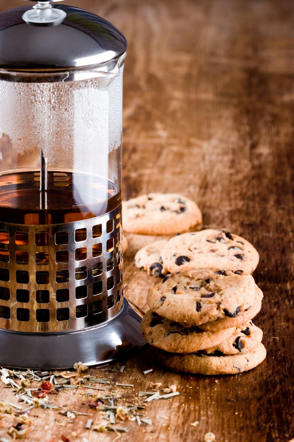 French press coffee maker, a glass carafe with a stainless steel mesh plunger and dark lid, beside chocolate chip cookies; Coffee and Tea Accessories