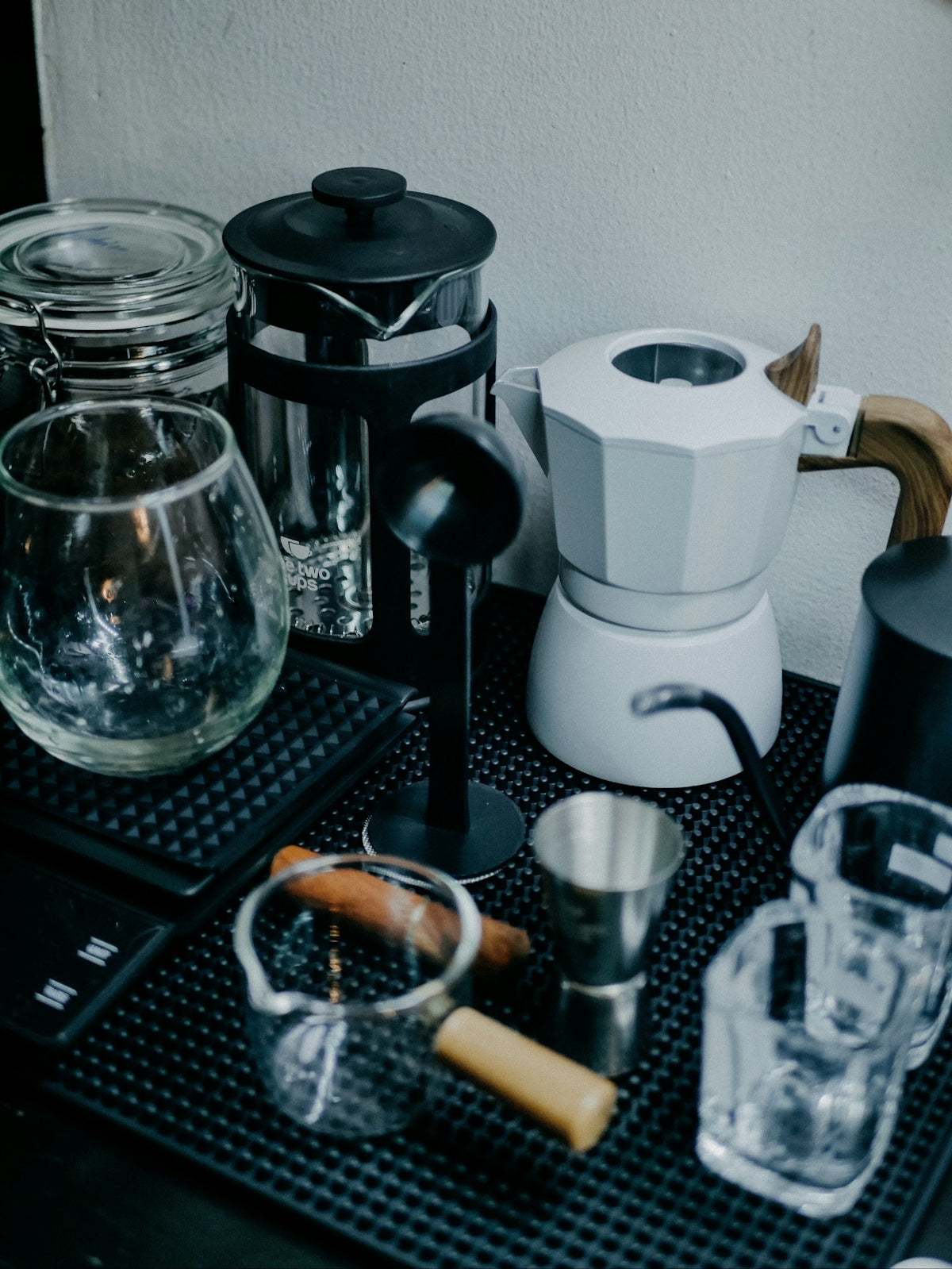 Coffee brewing equipment with black and white finishes, glass and metal parts, including a French press and moka pot; Comparative Review of Coffee Machines.