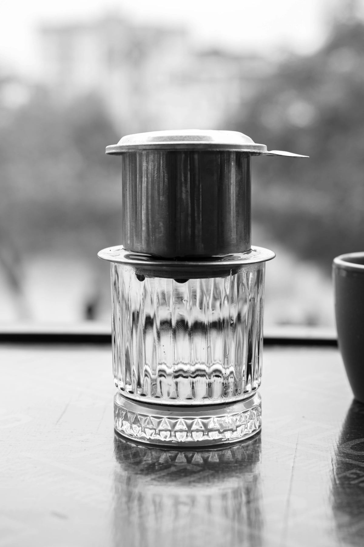 Vietnamese coffee filter brewing over a glass.